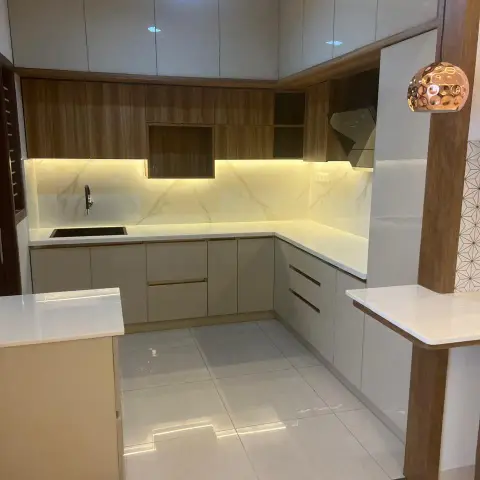 A two-tone U-kitchen in dove-grey gloss and walnut-grain laminate with a white quartz counter, a warm LED strip washing a marble-look dado