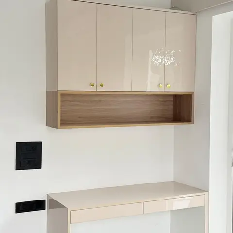 A wall-mounted study desk unit with glossy beige overhead cabinets, an open wood shelf, and a glossy console desk below.