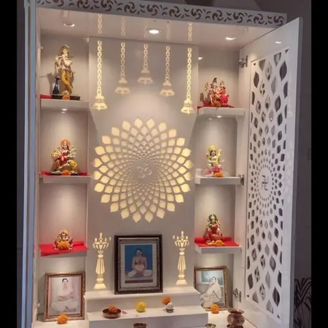 A white CNC-jaali temple-style pooja unit with three shikhara-tower finials, a backlit Om motif, and shelves of deity idols framed by a filigree cabinet door.
