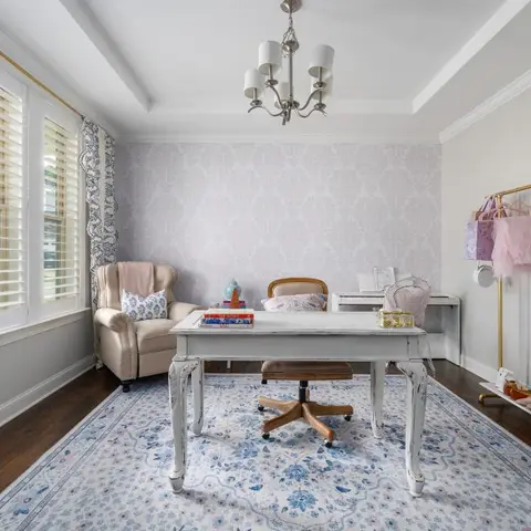 A white tray-ceiling study with a distressed white writing desk, a grey damask wallpaper accent wall