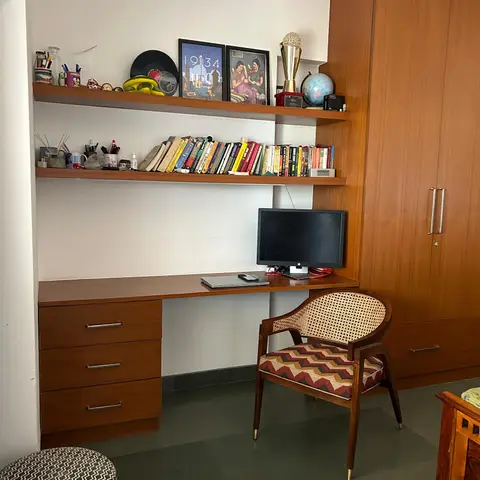 A wood-panelled study nook with built-in bookshelves and a desk, paired with a mid-century cane-back armchair in chevron-patterned upholstery.