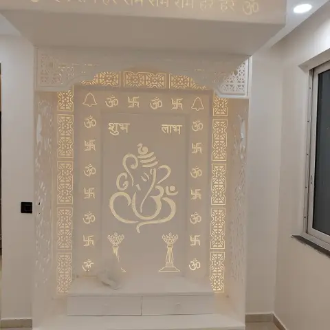 All-white backlit pooja mandir with a calligraphic Ganesha panel framed by Om and swastik borders