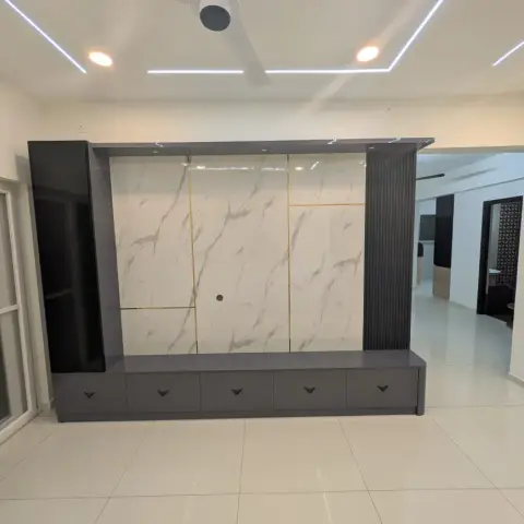 An empty living room TV wall with a gold-inlaid marble slab panel flanked by fluted grey pillars, a floating grey TV console
