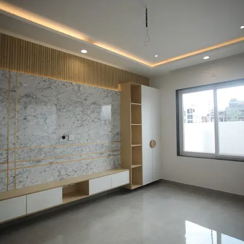 An empty living room with a book-matched marble TV feature wall trimmed in gold, flanked by vertical wood-slat cladding and a floating console