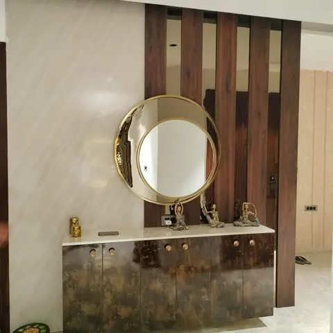 An entrance foyer console area with a round brass-framed mirror above a dark textured-lacquer cabinet with brass knobs