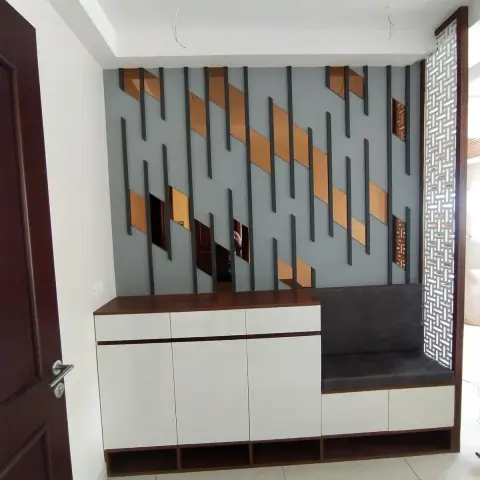 An entrance foyer shoe unit in white shutters with a walnut top and an upholstered grey seat at one end