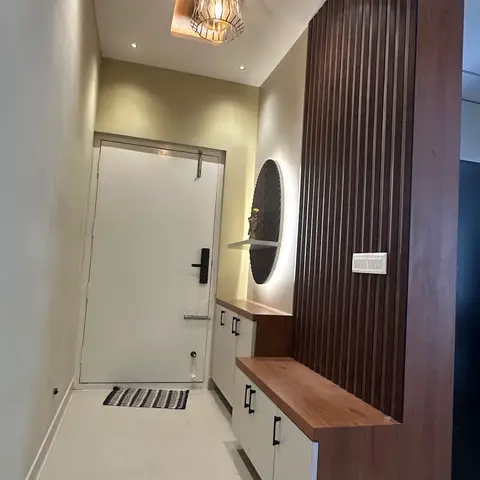 An entrance foyer with a caged pendant light in a wood-clad ceiling recess, fluted wood wall panelling