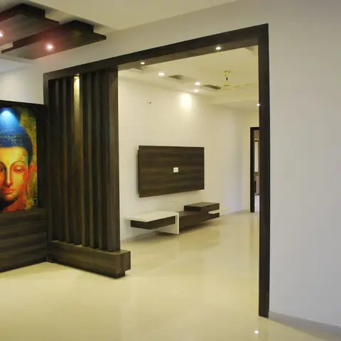 An entrance foyer with a dark wood console beneath a glowing Buddha wall-art panel, a vertical wood-slat partition column, and a box-panel cove-lit ceiling