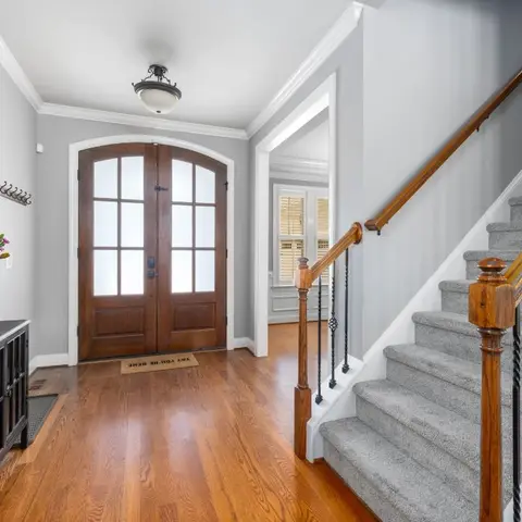 An entrance foyer with a double arched wood-and-glass front door and a black console table styled with fresh flowers