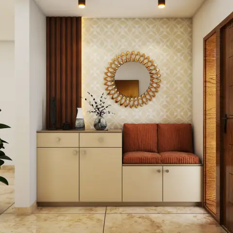 An entrance foyer with a geometric-pattern wallpaper wall, a gold sunburst mirror, a rust upholstered bench, and a cream storage cabinet below.