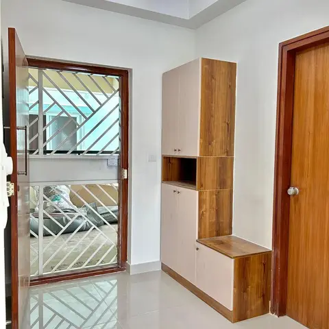 An entrance foyer with a wood-and-white shoe storage unit with an open display niche and integrated bench seat