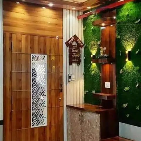 An entrance foyer with a wood-panelled main door featuring a laser-cut jaali insert beside an artificial moss accent wall and a marble-finish storage console.