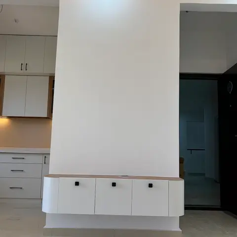 An entrance passage with a floating white console cabinet with a wood top and rounded ends, flanked by openings to the kitchen and front door.