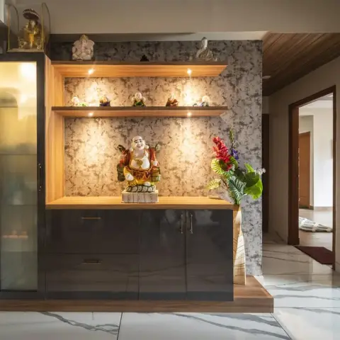 An entryway display console with a dark glossy cabinet base, warm-lit wood display niches showcasing statuettes and a large laughing Buddha figurine