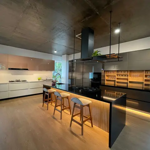 An industrial-style island kitchen with a black waterfall-edge island, a fluted wood stool-base panel