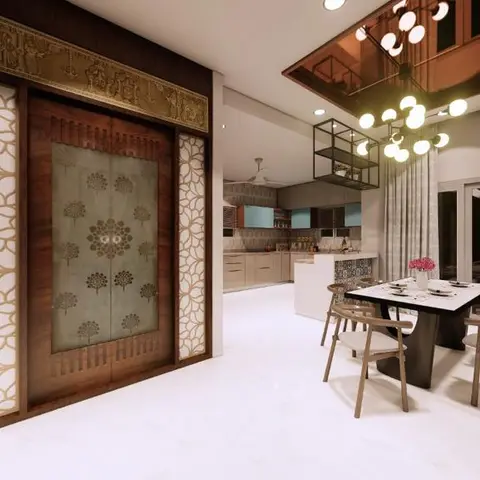 An open dining and kitchen area anchored by an ornately carved wood pooja-style door with brass toran and jaali side panels