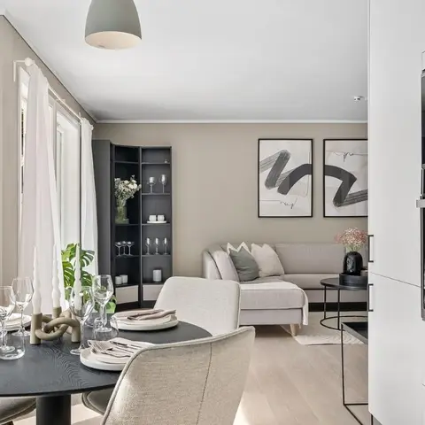 An open dining-living-kitchen space with a black round dining table set for four in the foreground