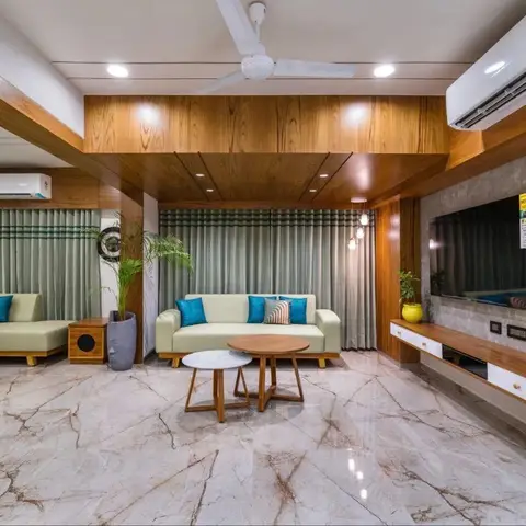 An open living room with a wood-paneled ceiling bulkhead, a stone-clad TV wall, and olive-green sofas with teal accent cushions on a veined marble floor.