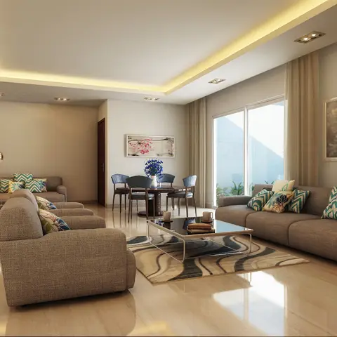 An open living room with two grey sectional sofas around a wave-patterned rug and a glass-and-brass coffee table, cove-lit ceiling