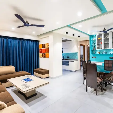 An open-plan apartment showing a brown sectional sofa living area, a glass-top dining table