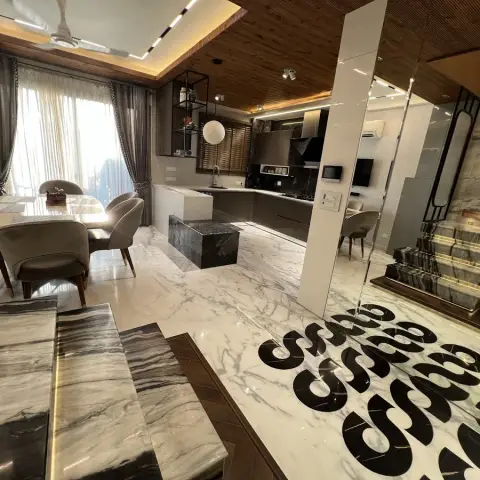 An open-plan dining-kitchen-foyer space with book-matched grey marble flooring featuring a bold graphic inlay pattern, a wood-slat ceiling