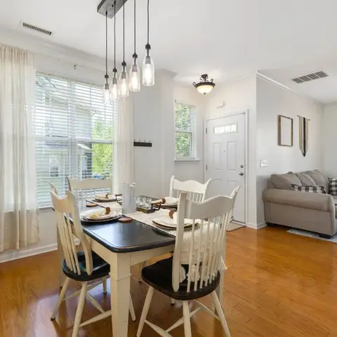 An open-plan dining nook with a black-and-cream farmhouse table under a cluster of glass pendant lights