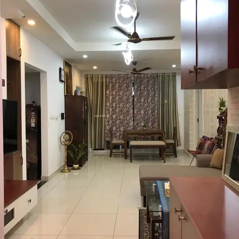 An open-plan hallway view showing a wood-panelled TV console on one side and a wood dining table with a bench in the adjoining dining area