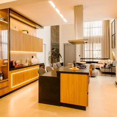 An open-plan kitchen with a black-and-wood island and a glass-front crockery display cabinet opens onto a living area with a sectional sofa.