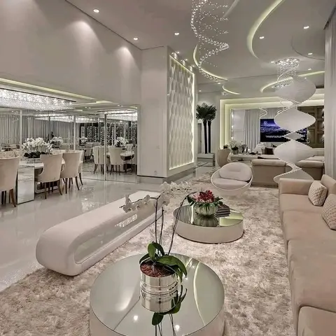 An open-plan living and dining hall with a sculptural curved false ceiling, spiral crystal chandeliers, mirrored wall