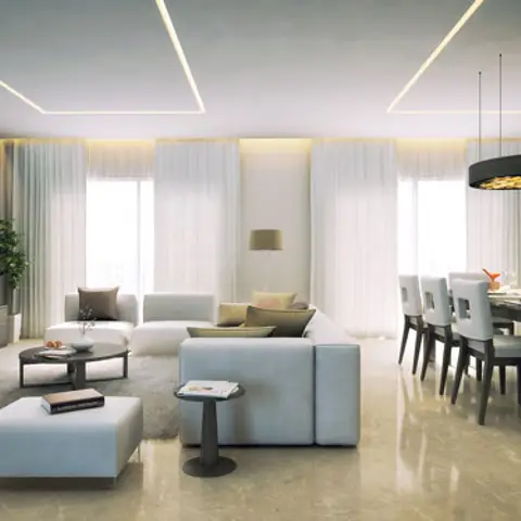 An open-plan living and dining room with a linear cove-lit ceiling design, a wall-mounted TV media unit, and a black drum pendant light over the dining table.