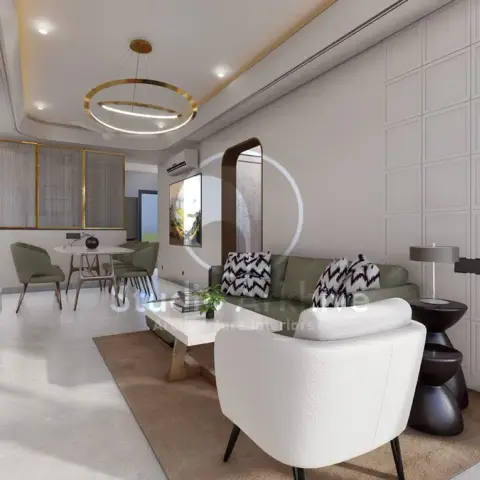 An open-plan living and dining space with a wood-panel TV wall, ring pendant light, arch mirror, and an olive-green sofa facing a marble-top coffee table.