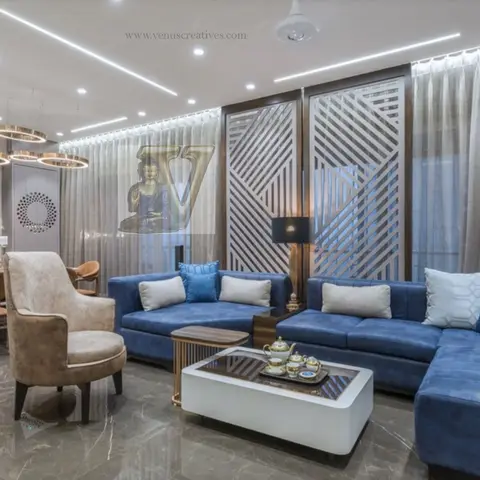 An open-plan living and dining space with a navy velvet L-shaped sectional sofa, a geometric diagonal jaali partition wall