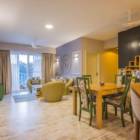 An open-plan living-dining room with olive wicker barrel chairs and a trunk coffee table on one side