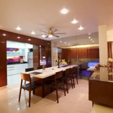 An open-plan space showing a wood-panelled dining area, a compact galley kitchen, and a leather sofa lounge with a glass-partitioned feature nook