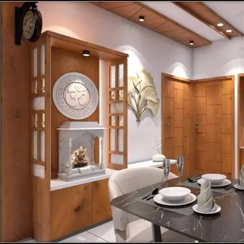 An open zone showing a wood-and-jaali pooja mandir with a carved marble Om medallion beside panelled entry doors and a set dining table.