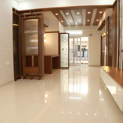 An unfurnished entrance area with a fretwork wooden partition unit, damask wallpaper feature wall and a cove-lit beamed ceiling