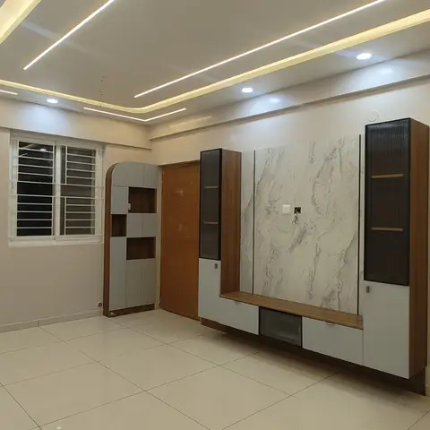 An unfurnished living room with a marble-slab feature wall behind a floating wood TV console flanked by fluted-glass display cabinets
