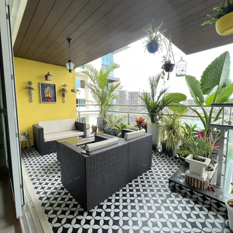 Apartment balcony floored in black-and-white four-petal pattern tiles, with two dark wicker sofas around a low glass table