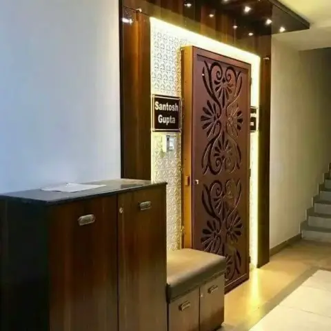 Apartment entrance foyer with a carved wood main door in a backlit niche, a wood-panelled ceiling recess with spotlights