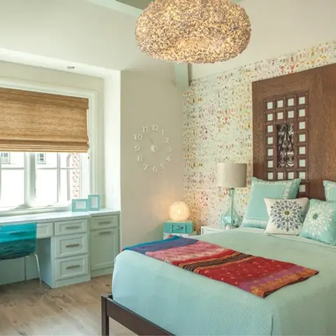 Aqua-and-cream bedroom where a pair of carved teak jaali door panels serve as the headboard, with a confetti-speckle wallpapered wall