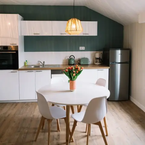 Attic kitchen-diner where a forest-green wall runs behind a white flat-front kitchen with oak laminate worktop and white metro tile band
