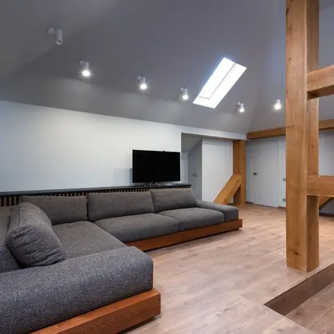 Attic loft living room with a sloped ceiling and skylight, exposed structural wood beams