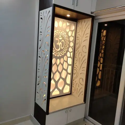 Backlit CNC-cut jaali pooja unit with an Om medallion over a lotus-petal pattern, set in a white niche with a stone platform