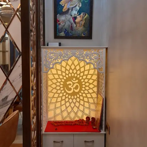 Backlit CNC-cut lotus jaali with a central Om behind a marble platform laid with a red cloth and marigold garlands
