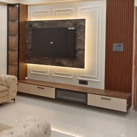 Backlit dark-marble TV panel framed in white moulded panelling beside fluted wood cladding, with tufted cream chesterfield sofas on glossy floor tiles.