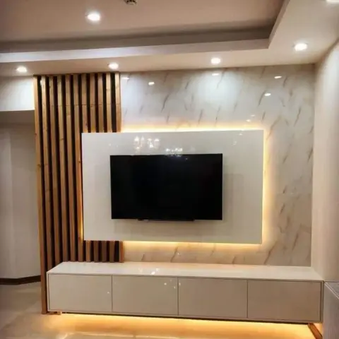 Backlit marble-panel TV wall beside a vertical wood-fluted partition screen, with a floating gloss console lit by a warm LED strip along its base.