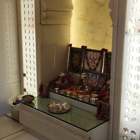 Backlit marble pooja unit with a Rajasthani-style arched onyx niche housing deity idols, flanked by perforated marble jaali panels