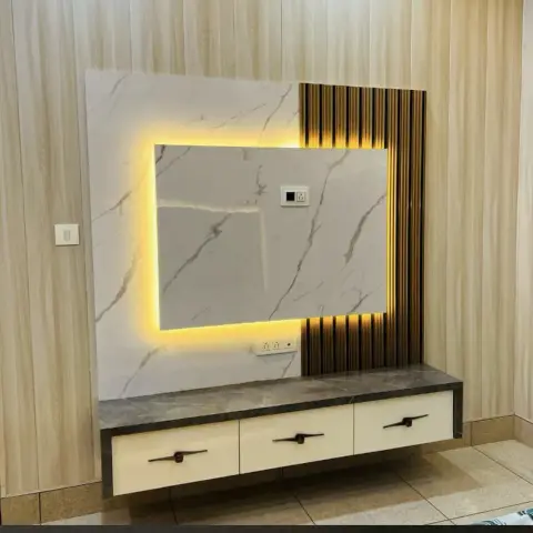 Backlit marble TV feature wall with brass-and-wood fluted panel strip beside a floating cream drawer unit