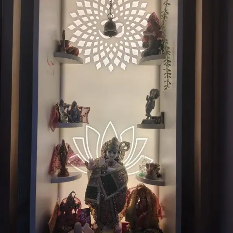 Backlit pooja niche with a laser-cut lotus and mandala light motif, floating stone shelves displaying deity idols, and a central Krishna statue.