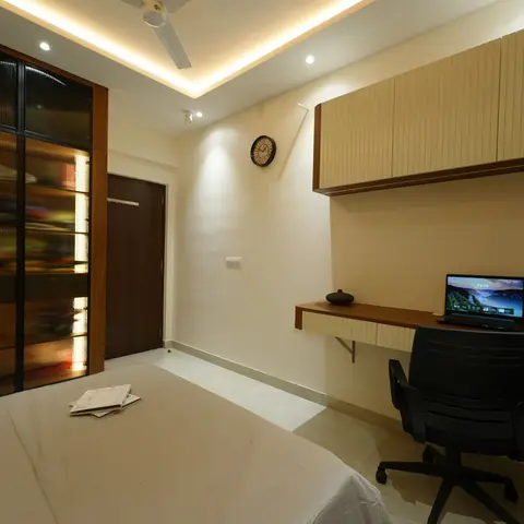 Backlit reeded-glass wardrobe in slim black frames facing a wall-hung teak study ledge with fluted overhead cabinets